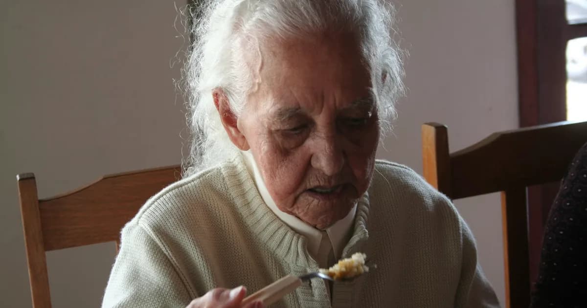 Idosa se alimentando, representando nutrição e saúde digestiva no cuidado com demência