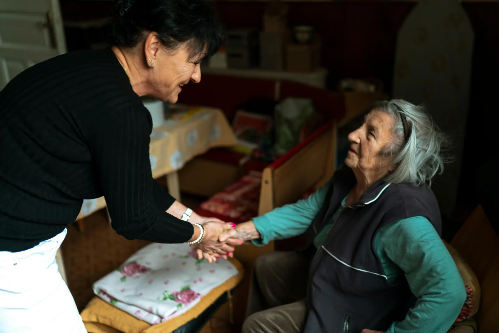Mãe e filha conversando sentadas no sofá, em um momento de conversa próxima e cuidadosa