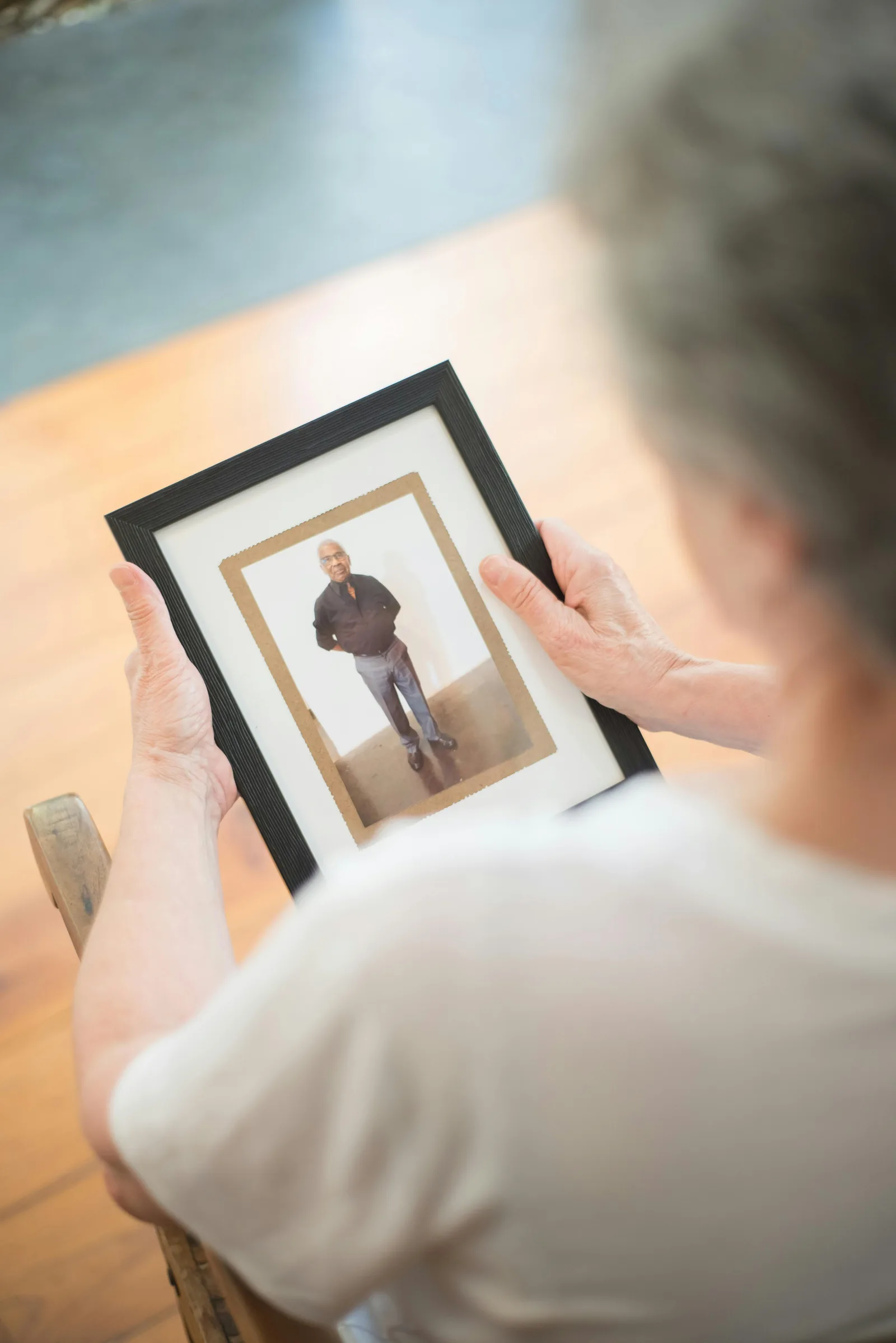 Mulher idosa olhando para uma fotografia antiga, expressando saudade e a dor de despedidas que começam ainda em vida.